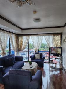 una gran sala de estar con sofás azules y TV. en 2BD, 2BR condo Penthouse, en Davao City