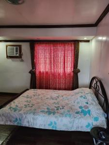 1 dormitorio con cama y cortina roja en 2BD, 2BR condo Penthouse, en Davao City