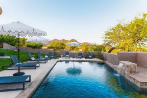 a swimming pool with lounge chairs and an umbrella at Julep by AvantStay Stylish 9 BR Estate w Mid-Century Modern Decor in Phoenix