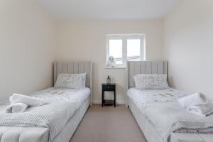 two twin beds in a room with a window at Premium Nights - Harry Potter, Professional, Family stay in Watford