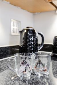 two glass mugs sitting on a counter with a tea pot at Premium Nights - Harry Potter, Professional, Family stay in Watford