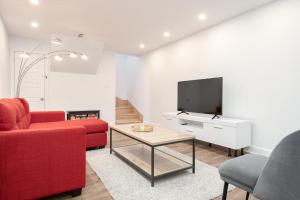 een woonkamer met een rode bank en een tv bij Contemporary renovated house in southshore MTL in Brossard
