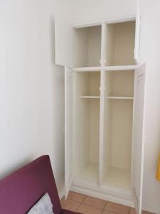 einen weißen Schrank mit weißen Regalen in einem Zimmer in der Unterkunft Superbe Studio de 23m² in Nîmes