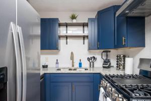 a kitchen with blue cabinets and a stainless steel refrigerator at Luxurious Extended Stay Dream~3 Kings~Desks~TV's in Snellville