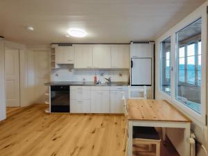 uma cozinha com armários brancos e uma mesa de madeira em Sunny Garden - Charmantes Chalet mit Aussicht em Aeschi bei Spiez