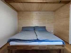 Cama en habitación con pared de madera en Sunny Garden - Charmantes Chalet mit Aussicht, en Aeschi bei Spiez