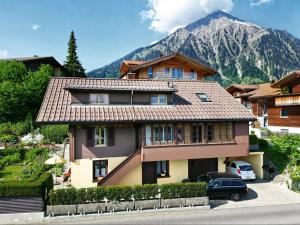 uma casa grande com uma montanha ao fundo em Sunny Garden - Charmantes Chalet mit Aussicht em Aeschi bei Spiez