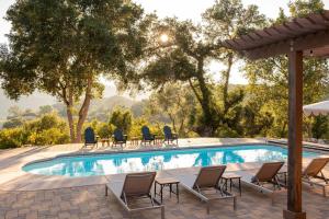 einen Pool mit Stühlen und einem Sonnenschirm in der Unterkunft Dolcetto by AvantStay Wine Country Mansion Minutes from Vineyards in Paso Robles