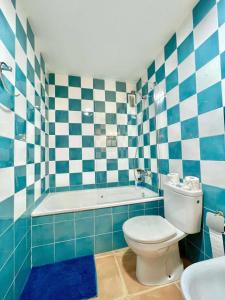 uma casa de banho azul e branca com um WC e uma banheira em Apartamento con vistas al mar piscina padel em Barrio-Mar