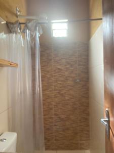 a bathroom with a shower with a toilet and a window at Chalé Beach Preá in Prea