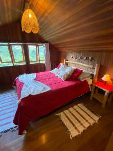 1 dormitorio con 1 cama roja grande en una cabaña en CHALÉ vista linda- VISCONDE DE MAUA, en Bocaina de Minas