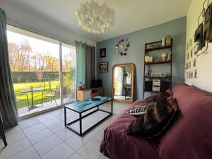 een woonkamer met een bank en een glazen tafel bij Ecrin de verdure Entre forêt et océan in Saint-Martin-de-Seignanx