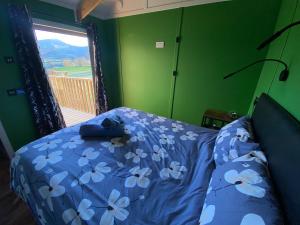 Schlafzimmer mit einem Bett mit blauer Bettwäsche und einem Fenster in der Unterkunft Hafan y Mynydd - Accessible double shepherd hut in Machynlleth