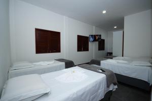 a room with three beds and a flat screen tv at Pousada Girassol in Maceió