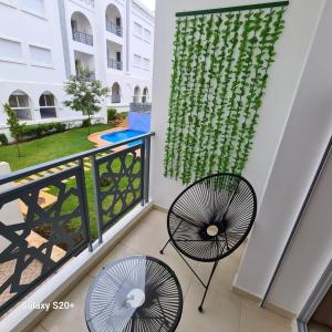 einen Balkon mit 2 Stühlen und einem Fenster in der Unterkunft Appartement complexe dream hills in Tangier
