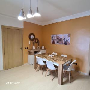 ein Esszimmer mit einem Tisch und weißen Stühlen in der Unterkunft Appartement complexe dream hills in Tangier