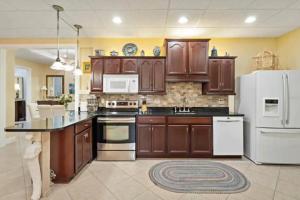 a kitchen with wooden cabinets and a white refrigerator at Tropical Pool Paradise - Minutes from the Beach Venice in Nokomis