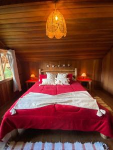 1 dormitorio con 1 cama grande de color rojo y 2 mesas en CHALÉ vista linda- VISCONDE DE MAUA, en Bocaina de Minas