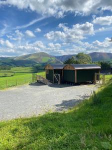 deux bâtiments situés sur le côté d’une route dans un champ dans l'établissement Hafan y Mynydd - Accessible double shepherd hut, à Machynlleth