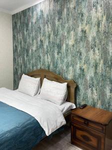 1 dormitorio con 1 cama con una pintura en la pared en City hotel, en Karakol
