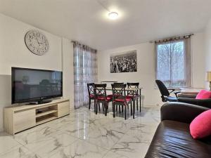 Una sala de estar con un televisor y una mesa con sillas. en Champs Harmony *Paris*Disney*, en Champs-Sur-Marne