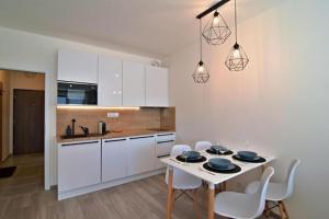 eine Küche mit weißen Schränken sowie einem weißen Tisch und Stühlen in der Unterkunft Apartment KORZO 318/3 in Lipno nad Vltavou