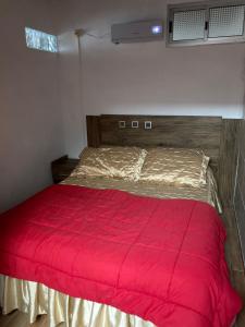 ein Bett mit einer roten Bettdecke in einem Schlafzimmer in der Unterkunft La Quimera del Águila in Atlántida