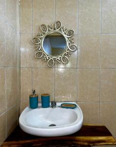 La salle de bains est pourvue d'un lavabo et d'un miroir sur un mur carrelé. dans l'établissement Desactivado, à Puerto Escondido