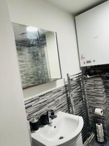 a bathroom with a white sink and a mirror at Town Centre Modern 1 Bed 1 Bath Apartment at Potter House by Lord Property in Aldershot