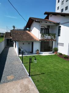 uma casa branca com um relvado à frente em RCM Vilas - Casa Confortável 02 em Joinville
