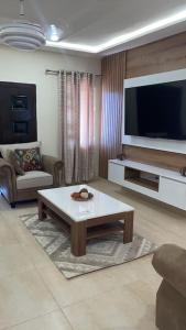 a living room with a coffee table and a flat screen tv at Luxury 3-bedroom apartment in Accra