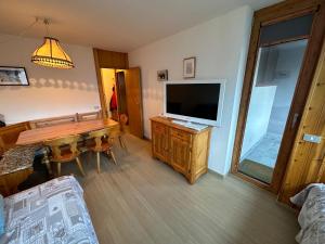ein Wohnzimmer mit einem TV und einem Holztisch in der Unterkunft Sasso Rosso Apartment in Folgarida