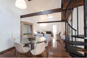 a dining room with a glass table and white chairs at PedrasNegras30 Lisbon Lofts & Apartments in Lisbon