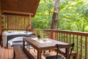 a wooden deck with a table and a bath tub at Foxview by AvantStayCabin 20min from Pigeon Forge in Gatlinburg