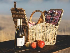 a basket and a bottle of wine and apples on a table at The Three Anchors Rooms in Emboríon