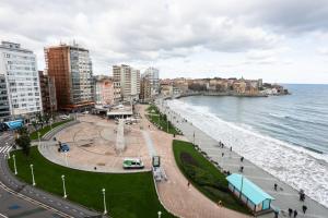 a view of a beach with buildings and the ocean at Amanecer Cantábrico in Gijón