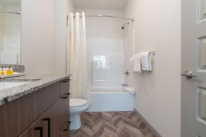 uma casa de banho branca com um WC e um chuveiro em Yugo Guest Suites em Urbana
