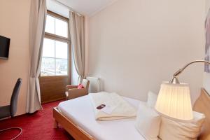 a hotel room with a bed with a lamp and a window at Moselhotel Römischer Kaiser in Bernkastel-Kues