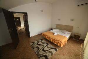 a bedroom with a bed with an orange comforter at Pensiunea Zbor in Cluj-Napoca