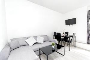 a white living room with a couch and a table at Strand Central Apartments in London