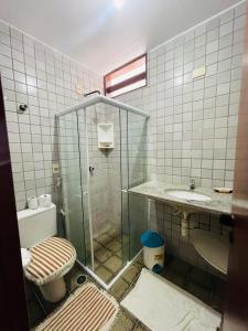 a tiled bathroom with a toilet and a sink at Condomínio Rochas do Mar in Barra de São Miguel