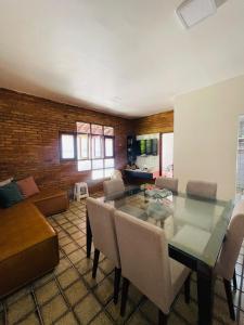 a living room with a glass table and chairs at Condomínio Rochas do Mar in Barra de São Miguel