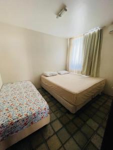 a bedroom with two beds and a window at Condomínio Rochas do Mar in Barra de São Miguel