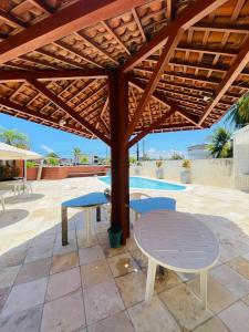 een houten pergola met een tafel en stoelen eronder bij Condomínio Rochas do Mar in Barra de São Miguel