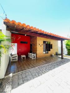 a house with a red door and a patio at Condomínio Rochas do Mar in Barra de São Miguel