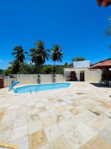 a swimming pool in a courtyard with palm trees at Condomínio Rochas do Mar in Barra de São Miguel