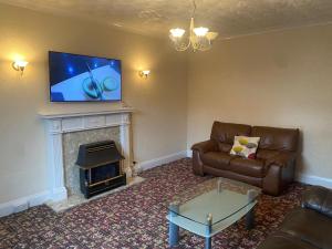 ein Wohnzimmer mit einem Sofa und einem TV über einem Kamin in der Unterkunft Spacious home near city hospital in Nottingham