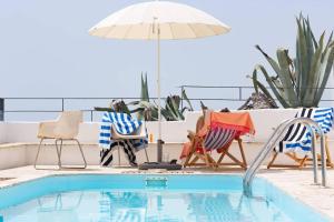 un grupo de sillas y una sombrilla junto a la piscina en Casa Condessa - Create memories, en Azenhas do Mar