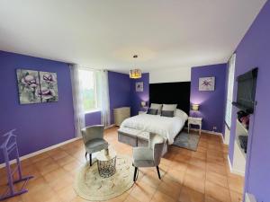 a bedroom with purple walls and a bed and chairs at Chambre d'hôte Lavande - Le soleil des Cévennes in Saint-Jean-du-Gard