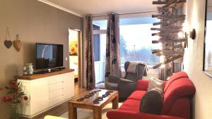 un salon avec un canapé rouge et une télévision dans l'établissement Ferienwohnung Abenddämmerung Hahnenklee, à Hahnenklee